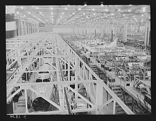 Production. B-17F heavy bombers. Overall view of a conveyor assembly line at the Long Beach, California, plant of Douglas Aircraft Company, showing B-17F fuselages going through and, at right, sectional fuselage jigs in which fuselage halves are assembled from prefabricated parts. Better known as th