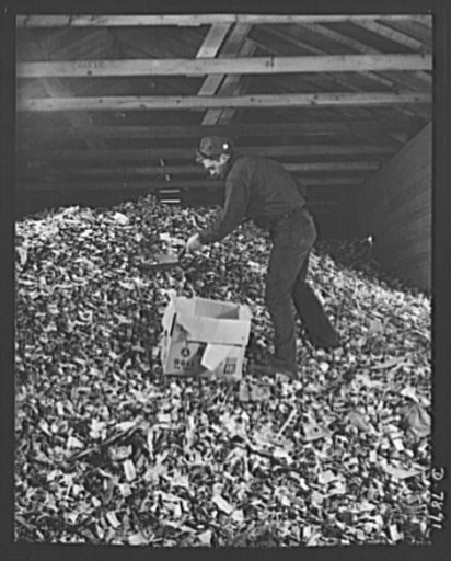 Empty collapsible tubes: a tin mine for war industry. Some of the millions of old tooth paste, shaving cream and other metal tubes received at the Newark, New Jersey reclamation plant of the Tin Salvage Institute. Frank Thomas, age 19, works at the trimming of the huge pile of squeezed-out tubes