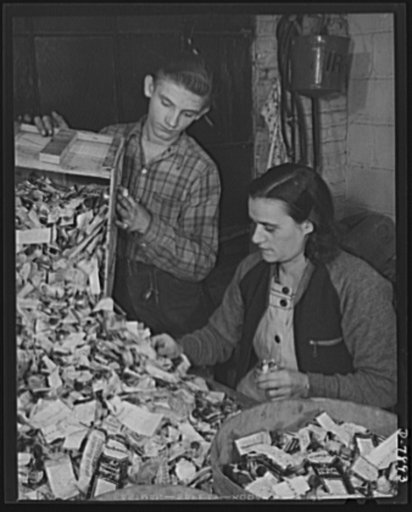 Empty collapsible tubes: a tin mine for war industry. Squeezed-out metal tubes, donated by patriotic Americans, are sorted in the Newark, New Jersey plant of the Tin Salvage Institute. Tin and lead are separated from containers made of aluminum and other metals. James Butler, age 18, is waiting for 