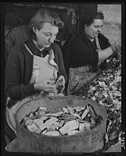 Empty collapsible tubes: a tin mine for war industry. Sorting used metal tubes at the Newark, New Jersey reclamation plant of the Tin Salvage Institute. Tubes made of different metals are segregated into separate bins