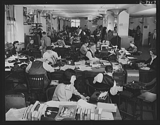 Office of War Information News Bureau. The News Bureau room of the OWI. It is arranged much the same way as the city room of a daily newspaper. Here, war news of the world is disseminated. In the foreground, are editors' desks handling such special services as trade press, women's activities, and ca