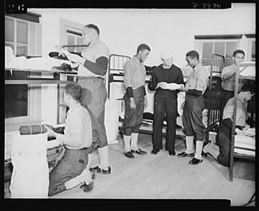 Manhattan Beach Coast Guard training station. Bag inspection in barracks of Company 24 at Mahattan Beach Coast Guard training station is a daily chore. Company Commander Paul L. Perkins is shown inspecting equipment of enlistees and showing new recruits how to roll equipment so that it can fit into 