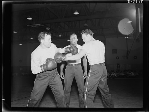 Manhattan Beach Coast Guard training station. Lou Ambers, former world's lightweight champion, sparring with Marty Servo, well-known pro, as Eristus Sams, former Tuskegee football and track star, referees. All three are boxing instructors at the Manhattan Beach Coast Guard training station
