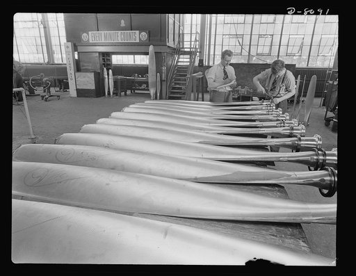 Production. Airplane propellers. New Hamilton propeller blades are inspected after face and camber profiling operations in a Hartford, Connecticut, plant. R. Ten Eyck checks the records and F. Breen, with a hammer and stamping die, puts the mark of approval on the butt of the blades
