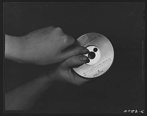 Conservation. Glass gauges replacing steel. Inspecting a gear with a  steel ring, since replaced by a glass gauge at the Frankford Arsenal. Glass gauges are lighter and cheaper than steel, permit greater visibility in inspection, are not as much affected by room temperatures and heat of operators' h