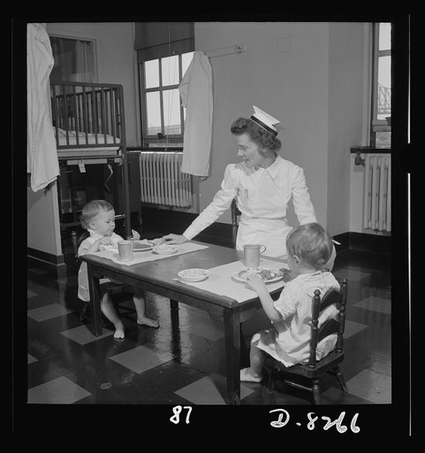 Nurse training. Convalescent children in a hospital are allowed to sit up at a table and eat just as soon as they are able. The nurse sits near for sociability and to help if she is needed