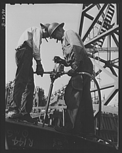 Manpower. Shipyard workers. Reaming holes in a deck plate for a new cargo boat under construction at the Wilmington, California, yard of the California Shipbuilding Corporation. The Booker T. Washington, recently launched at this yard, is one of the many freighters the company has built since Pearl 