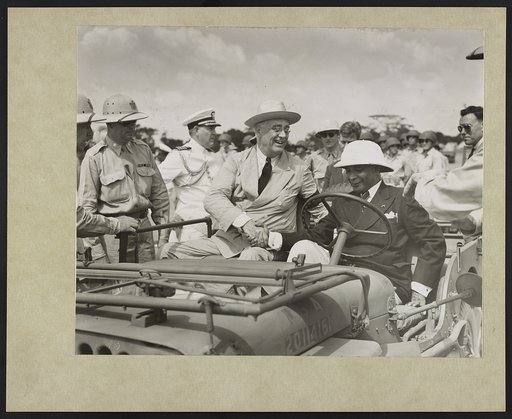 With a warm handclasp, President Roosevelt welcomes President Edwin Barclay of Liberia to an American jeep as they begin a review of American Negro troops stationed in the strategic African Republic