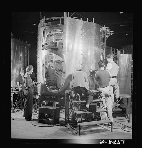 Production. B-17 heavy bomber. A crew of fast, expert workers at the Boeing plant in Seattle rivet a fuselage section for a new B-17F (Flying Fortress) bomber. Working on the section in the vertical position saves much valuable floor space. The Flying Fortress has performed with great credit in the 