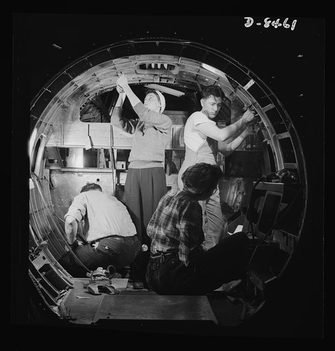 Production. B-17 heavy bomber. A skilled team of men and women workers at the Boeing plant in Seattle complete assembly and fitting operations on the interior of a fuselage section for a new B-17F (Flying Fortress) bomber. About half of the workers at the Boeing plant are women. The Flying Fortress 