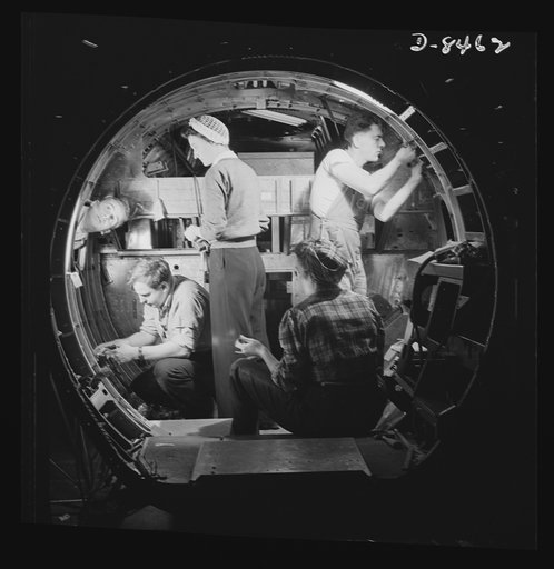 Production. B-17 heavy bomber. A skilled team of men and women workers at the Boeing plant in Seattle complete assembly and fitting operations on the interior of a fuselage section for a new B-17F (Flying Fortress) bomber. About half of the workers at the Boeing plant are women. The Flying Fortress 