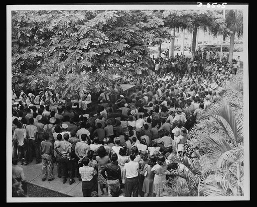 A Navy band entertains civil service employees during their lunch hour. Platforms have been built in strategic points near each shop and workers take delight in playing their noon shows from shop to shop