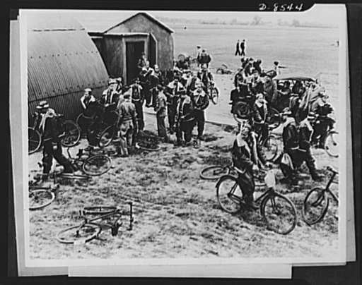 One year of reciprocal aid. American pilots emerge from the briefing room at a British airfield and mount their bicycles to proceed to their craft. Britian has turned over thousands of bicycles to the American forces