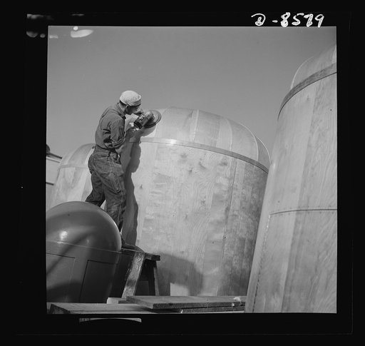 Conversion. Rowing shells to life rafts. Smooth and shiny as satin instrument covers made from plywood undergo final sanding. The worker operating the electric sander made rowing shells before the plant where he is employed converted to war production