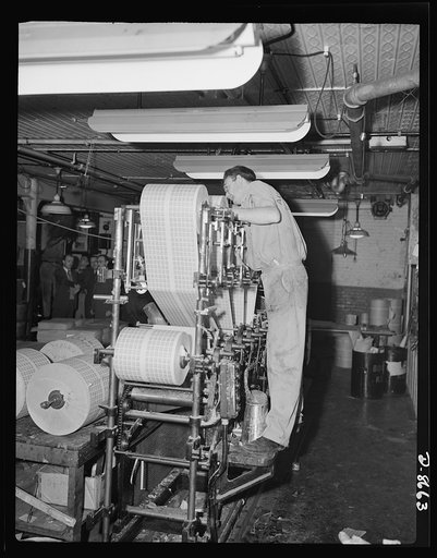 Printing war ration book 2. Another view of the collator with Otto Krantz checking the operation of the collating machinery. Note the glue can at his feet