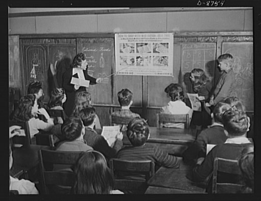 Preparation for point rationing. Catherine M. Rooney, 6th grade teacher at the Murch Elementary School, Washington, D.C., explains to her interested pupils how to use war ration book two when shopping for processed foods