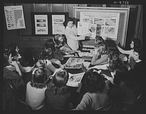 Preparation for point rationing. Home economics pupils of the Wilson Senior High School, Washington, D.C., learn the facts about war ration book two, and talk over ways in which homemakers can get well-balanced meals. An advanced student leads the class