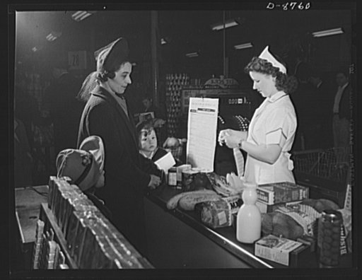 Preparation for point rationing. While a shopper and her children look on, the clerk tears point stamps from war ration book two to cover processed foods being purchased