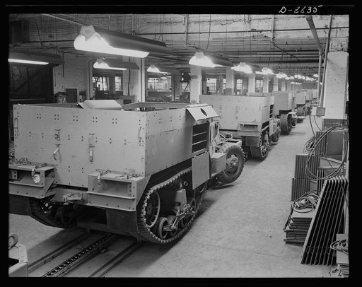 Production. Halftrac armoured cars. Partly finished halftrac scout cars travel along a moving assembly line in a plant converted from the manufacture of safes and locks. The bodies are made in this plant and mounted on chassis produced in a converted automobile plant. Diebold Safe and Lock Company, 