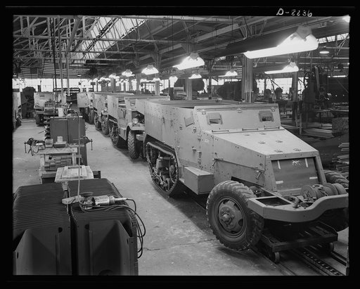 Production. Halftrac armoured cars. Partly finished halftrac scout cars travel along a moving assembly line in a plant converted from the manufacture of safes and locks. The bodies are made in this plant and mounted on chassis produced in a converted automobile plant. Diebold Safe and Lock Company, 
