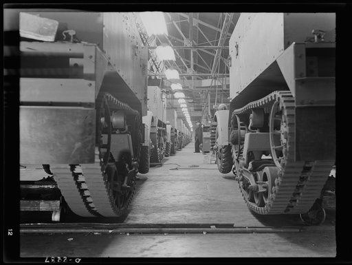 Production. Halftrac armoured cars. Partly finished halftrac scout cars travel along a moving assembly line in a plant converted from the manufacture of safes and locks. The bodies are made in this plant and mounted on chassis produced in a converted automobile plant. Diebold Safe and Lock Company, 