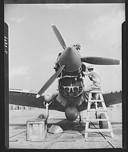 American "steam chickens" arrive in Africa. Wheeled out to the airfield, mechanics put finishing touches on meter and cowling of P-40 plane shortly after its arrival at an African port