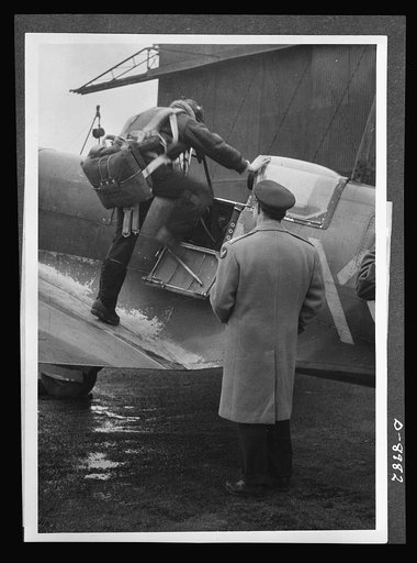 Reciprocal aid. Lieutenant E.S. Schofield, of Belleville, Ohio and Lieutenant R.F. Sargent of Youngstown, Ohio, pictured in Britain, as the former prepares to pilot a Spitfire plane. Lieutenant Schofield is using a British flying kit and Lieutenant Sargent is wearing a British Irvin jacket, part of 