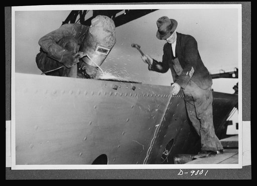 Reciprocal aid. Australian shipbuilding at work on a naval corvette. The hammering insures against scales adhering to joints to be welded. Many new shipyards have been established in Australia for an enlarged naval ship program