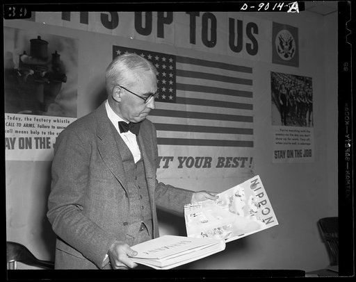Axis propaganda. Elmer Davis, director of the Office of War Information, examines Nazi and Japanese propaganda organs which he displayed at a press conference on March 6, 1943, to show material the Axis is distributing in neutral countries and the material with which the OWI is fighting it