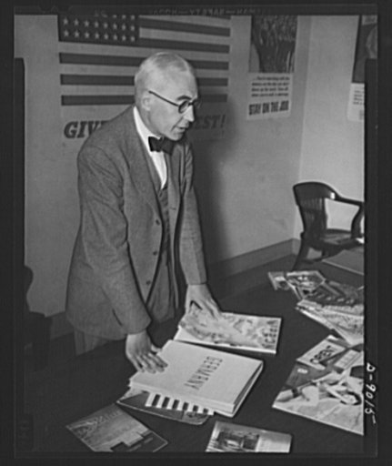 Axis propaganda. Elmer Davis, director of the Office of War Information, examines Nazi and Japanese propaganda organs which he displayed at a press conference on March 6, 1943, to show material the Axis is distributing in neutral countries and the material with which the OWI is fighting it