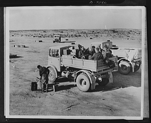 8th Army in Tripoli. At a British 8th Army fuel depot in the Western desert of North Africa a truckload of British Tommies stops while the driver refuels. Squares of gasoline cans, evenly spaced, are spread out across the flat land, as far as the eye can reach in preparation for the Tripoli campaign