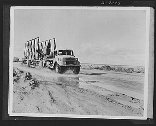 8th Army in Tripoli. A Royal Air Force salvage unit plows through mud and water carrying replacement parts which will return a damaged plane to action in the Tripoli campaign