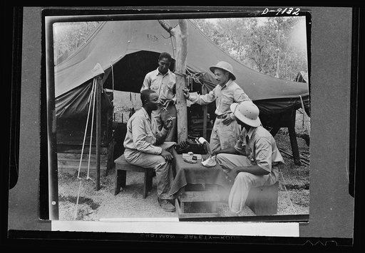 U.S. Negro troops in New Guinea. First Lieutenant Theodore R. Frierson, Chaplain, U.S. Army, holding a conference with several soldiers. Chaplain Frierson, aside from his regular duties, has become extremely popular with New Guinea troops, because of his promotion of a weekly "Soldier's Hour," a var