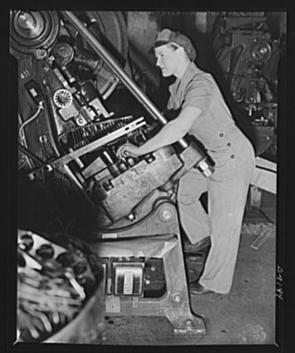 Virginia Ludwig goes to work on a punch press, stamping out discs from steel strips. Her well-fitting uniform is devoid of unnecessary pleats, trimmings, doodads--is just right for the job