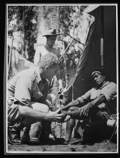 Natives aid Allied drive in New Guinea jungles. New Guinea natives receive the same medical attention as Allied troops, since their work is of vital aid to the Allied forces. Corporal McNicol, medical orderly at one of the forward outposts in the New Guinea jungle, attends one of the native carriers