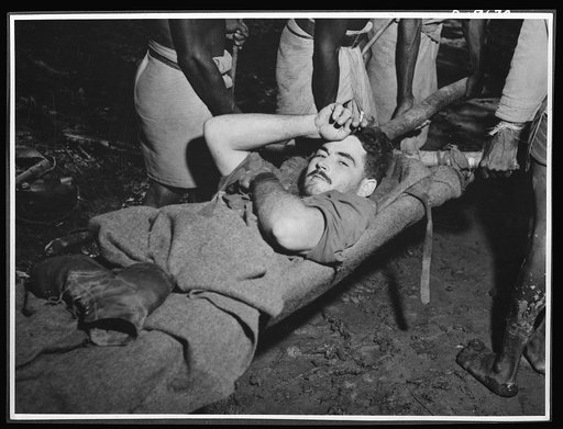 Natives aid Allied drive in New Guinea jungles. Corporal R.D. Somerville being taken from a dressing station in New Guinea just after the fighting at Oive. Without the native carrier service, Allied casualties would have been greater in this area