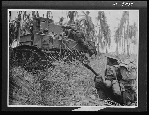 Troops in Australia. An American light tank, manned by an Australian crew, smashed through Japanese pillboxes in the final assault on Buna. This picture, taken during the actual fighting, shows an infantry commander jumping on the tank to warn the crew of a pillbox at the right, which the tank blast