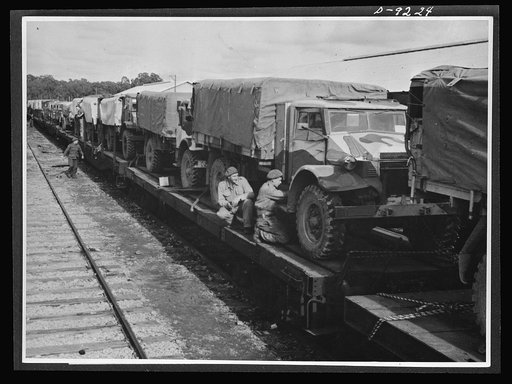 Australia in the war. American trucks, furnished under lend-lease, play an important role in Australian troop movements from training camps to battle stations. Drivers are shown attending to final details before the train moves off