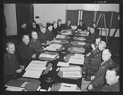 Combined Munitions Assignments Board. Combined Munitions Assignments Board at weekly meeting in Washington, with Chairman Harry Hopkins presiding. Staff officers seated at the conference table in the foreground are Brigadier L.F.S. Dawes (British); Air Vice Marshal W.F. MacNeece Foster (British); Li