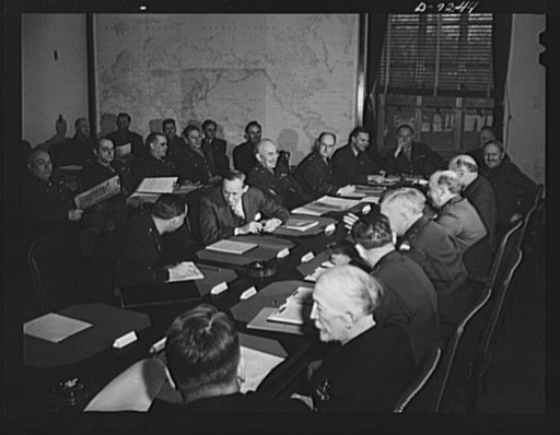Combined Munitions Assignments Board. Combined Munitions Assignments Board at weekly meetings in Washington, with Chairman Harry Hopkins presiding. Staff officers in the background, attend the meetings. Seated at the conference table clockwise are the following: Major General L.D. Clay (American); H