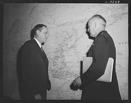 Combined Munitions Assignments Board. Chairman Harry Hopkins, of the Combined Munitions Assignments Board, confers with Major General J.H. Burns, executive officer of the board, before a huge world map at the board's conference room in Washington