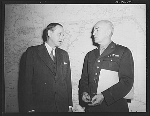 Combined Munitions Assignments Board. Chairman Harry Hopkins, of the Combined Munitions Assignments Board, confers with Major General J.H. Burns, executive officer of the board, before a huge world map at the board's conference room in Washington