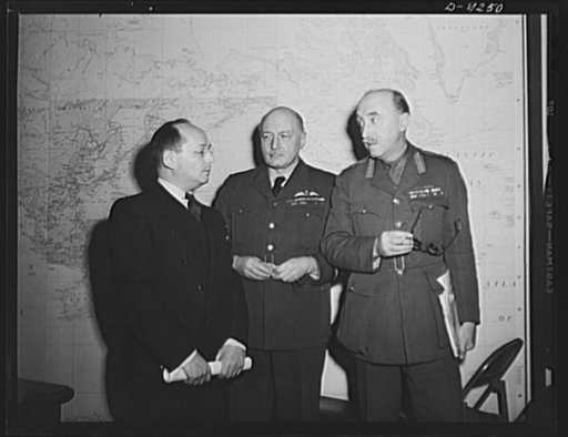Combined Munitions Assignments Board. American and British officials of the Combined Munitions Assignments Board discuss their problem before the world map in the conference room of the board in Washington. Left to right are: Dr. I. Lubin (American); Air Vice Marshal W.F. MacNeece Foster (British); 