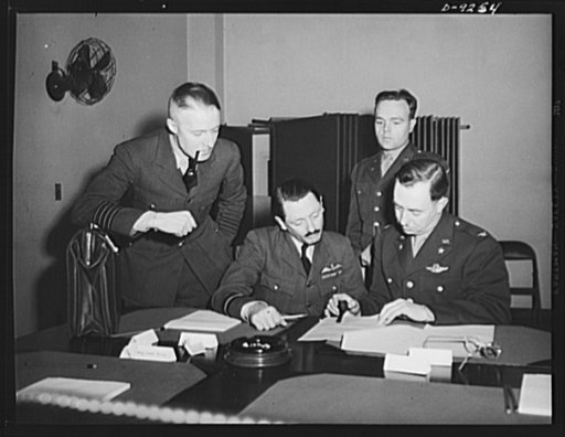 Combined Munitions Assignments Board. Staff members of the Combined Munitions Assignments Board compare data at weekly meeting of the board in Washington. Left to right are: Wing Commander R.C. Storiar (British); Air Commodore H.T. Lydford (British); Colonel E.C. Langmead (American); and Captain D.S