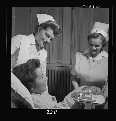 Nurse training. A nurse's aide and a student attend a convalescing patient