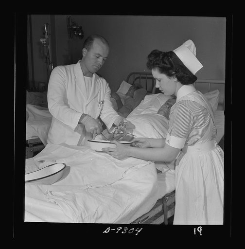 Nurse training. A student nurse assists the doctor in changing the dressing following an abdominal operation