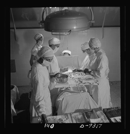 Nurse training. Calm and capable, these nurses are assisting at an appendectomy. The nurse in the foreground is arranging instruments to be handed to the surgeon