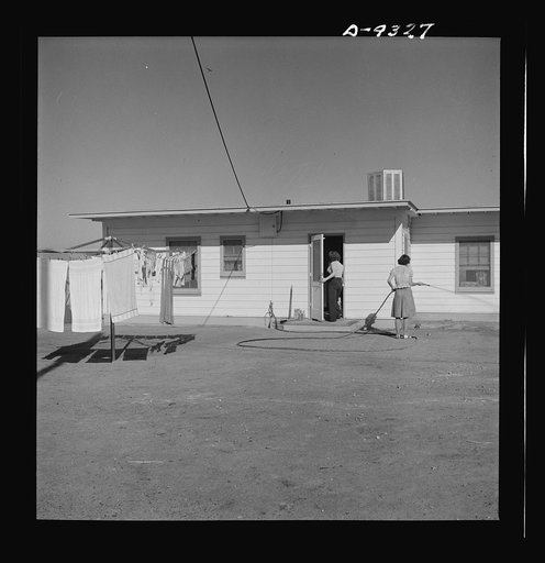Production. Magnesium. A worker's wife waters the newly planted lawn around one of the 1,000 demountable houses built in the southern Nevada desert adjacent to Basic Magnesium's giant Las Vegas plant
