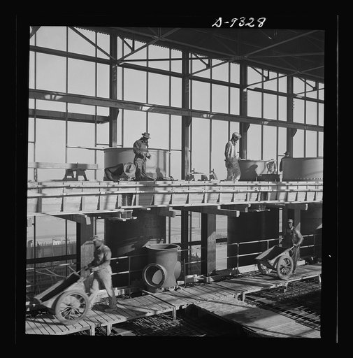 Production. Magnesium. High above the desert workmen speed up the reinforced steel construction of one of the 300-foot-long chlorination buildings at Basic Magnesium's huge plant in the southern Nevada desert
