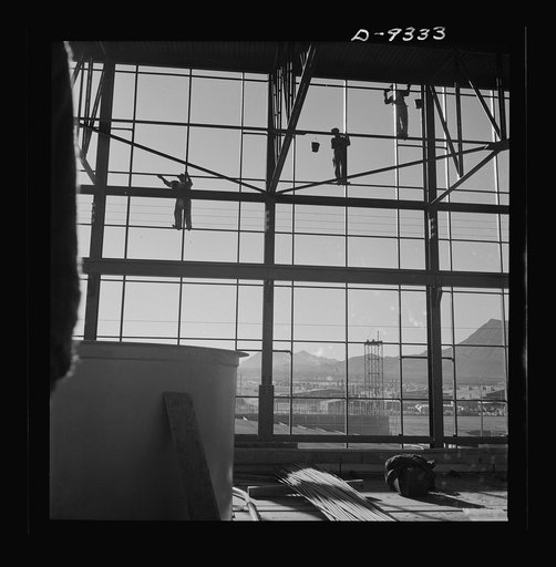 Production. Magnesium. Workmen seventy feet above ground are busily engaged in adding to the already gigantic proportions of Basic Magnesium's plant in the southern Nevada desert. A 24-hour production schedule results in turning out great quantities of magnesium for aircraft and tracer bullet manufa